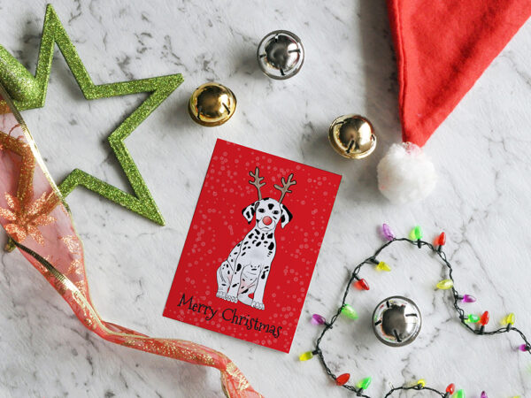 Red Christmas card featuring a cartoon Dalmatian wearing reindeer antlers, surrounded by Chrismtas decorations.