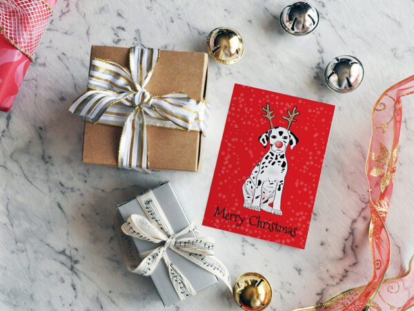 Red Christmas card featuring a cartoon Dalmatian wearing reindeer antlers, surrounded by small gifts and Christmas decorations.