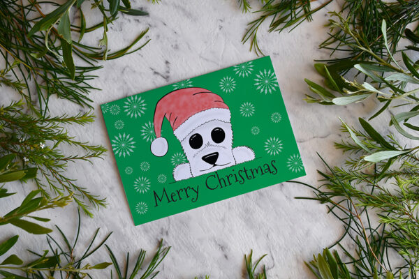 Green Christmas card featuring cartoon Westie in a Santa hat on a marble background surrounded by greenery.