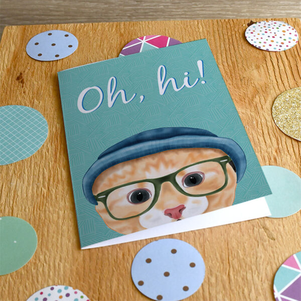 A card featuring a cartoon hipster Ginger cat in a beanie and glasses on a wooden background with various patterned paper polka dots.