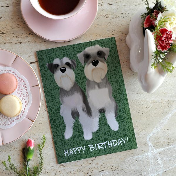 Schnauzer twins on a birthday card surrounded by macaroons and flowers