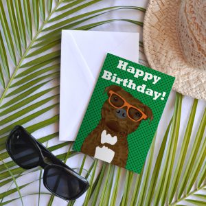 Brindle Staffy Buddy on a birthday card wearing orange glasses on a green background