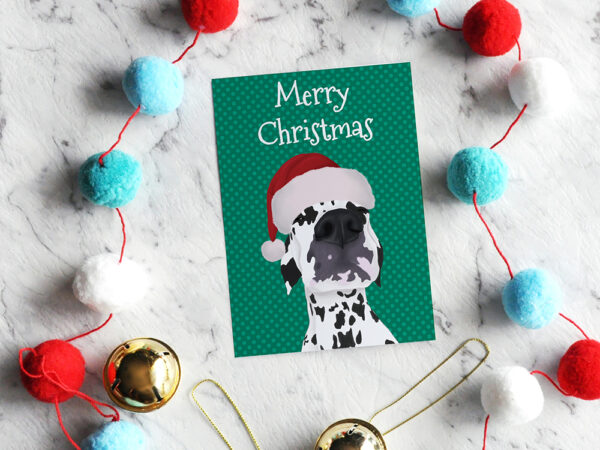 A Christmas card featuring a close up of the face of a Dalmatian in a Santa hat.