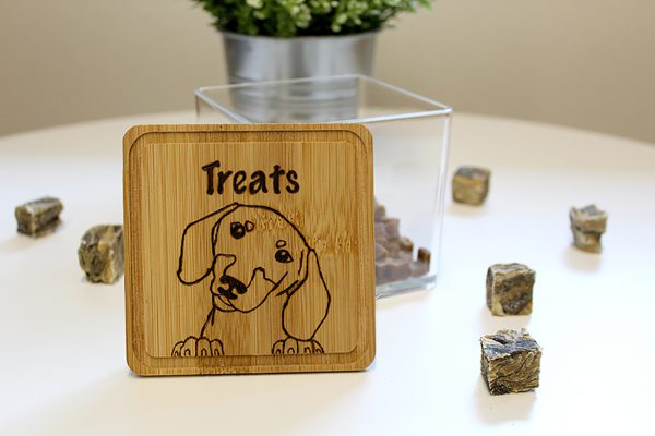 Plastic treat box with wooden lid in front with image of Dachshund burned in